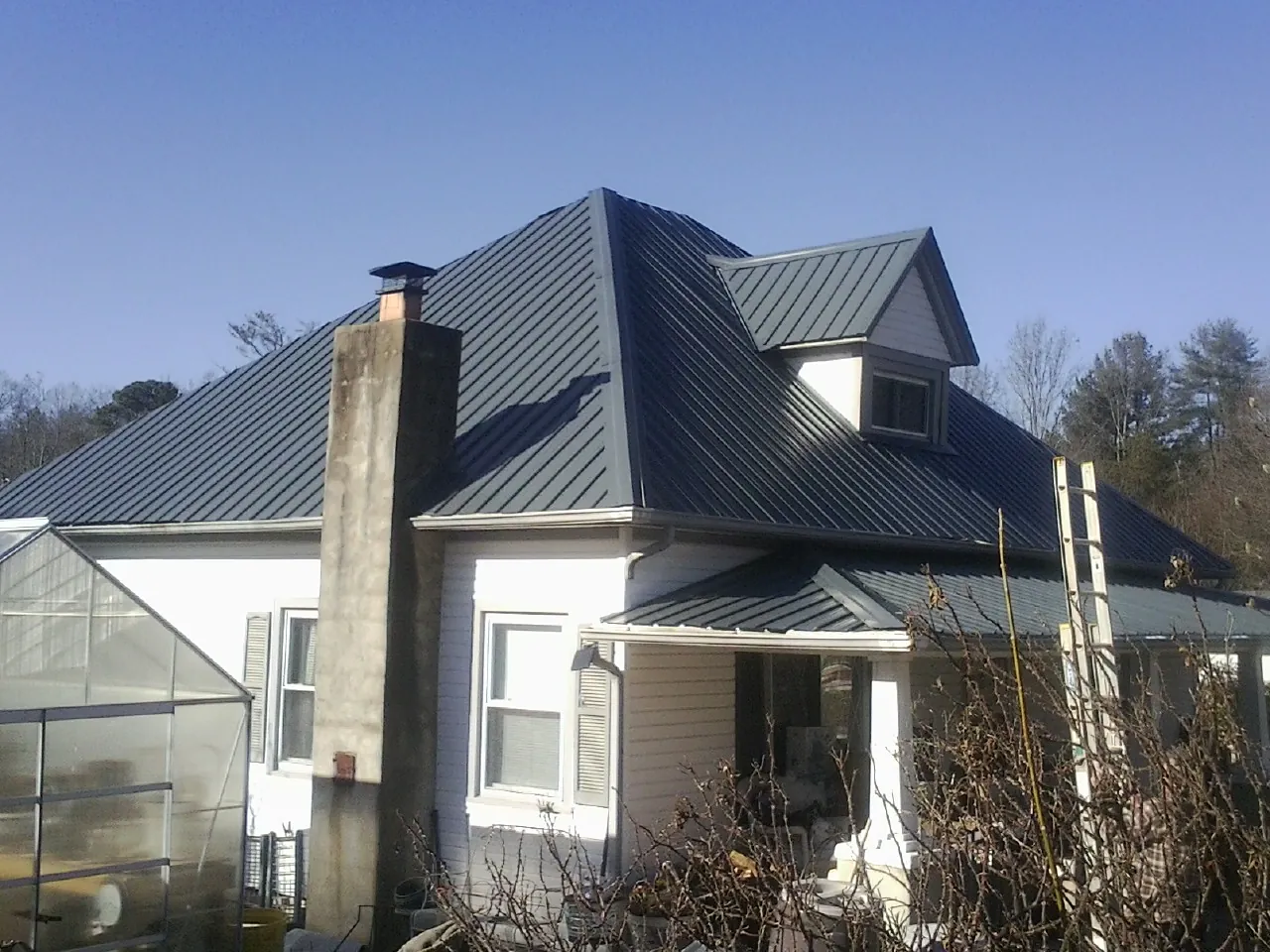 Dark blue standing seam metal roof on a white farmhouse with dormer — Slate & Tile Roof Repair by Roofing Brothers in Sultan