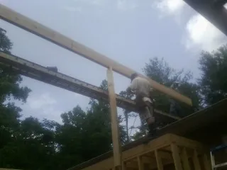 Carpenter setting a ridge beam over a new addition frame — Ice Dam Removal by Roofing Brothers in Sultan