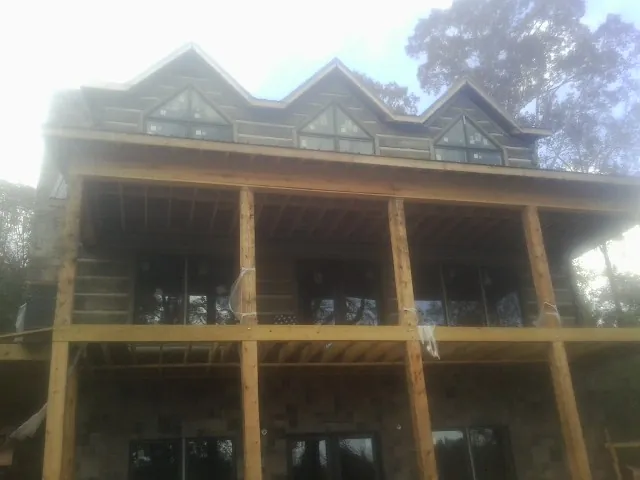 Dormers and porch framing on a large log home under construction — Roof Coating work by our crew in Sultan