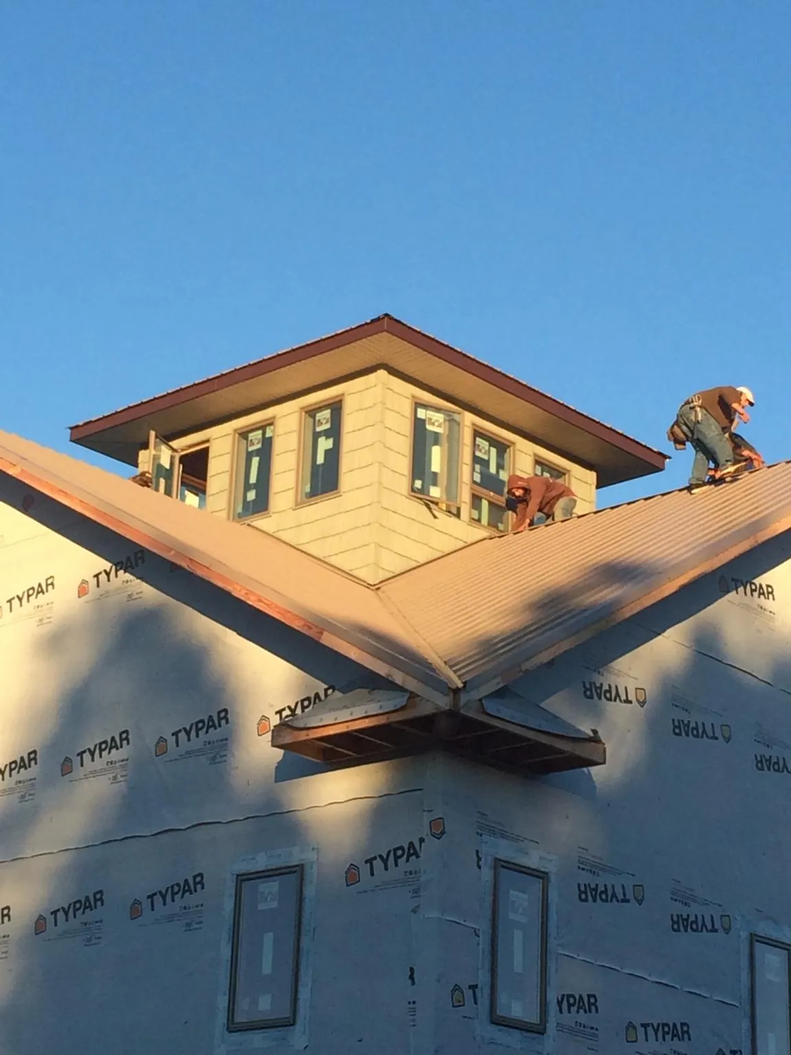 Roofers working around a rooftop cupola on a new metal roof at sunset — Roof Waterproofing in Sultan by Roofing Brothers